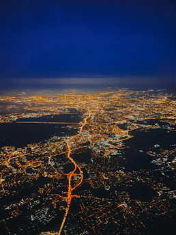 A sleek, glowing aerial view of a futuristic Indonesian city at night, with digital overlays highlighting smart infrastructure.