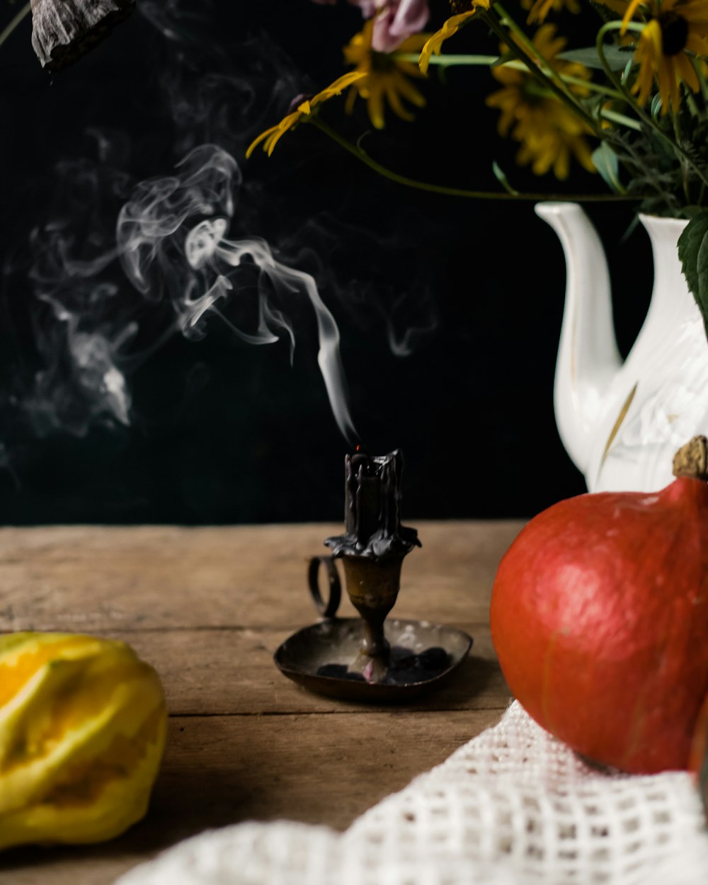a vase filled with flowers and smoke next to an apple