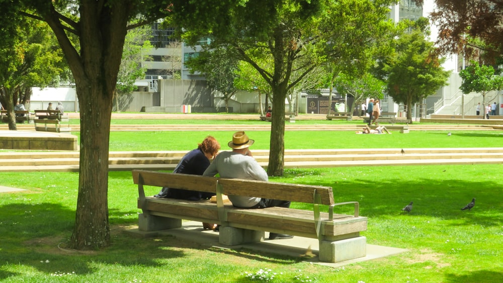 two people sitting on a bench in a park