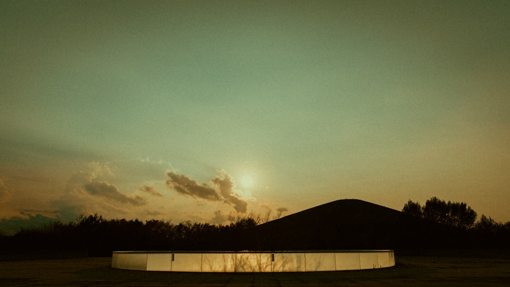 the sun is setting over a large pool in the middle of a field