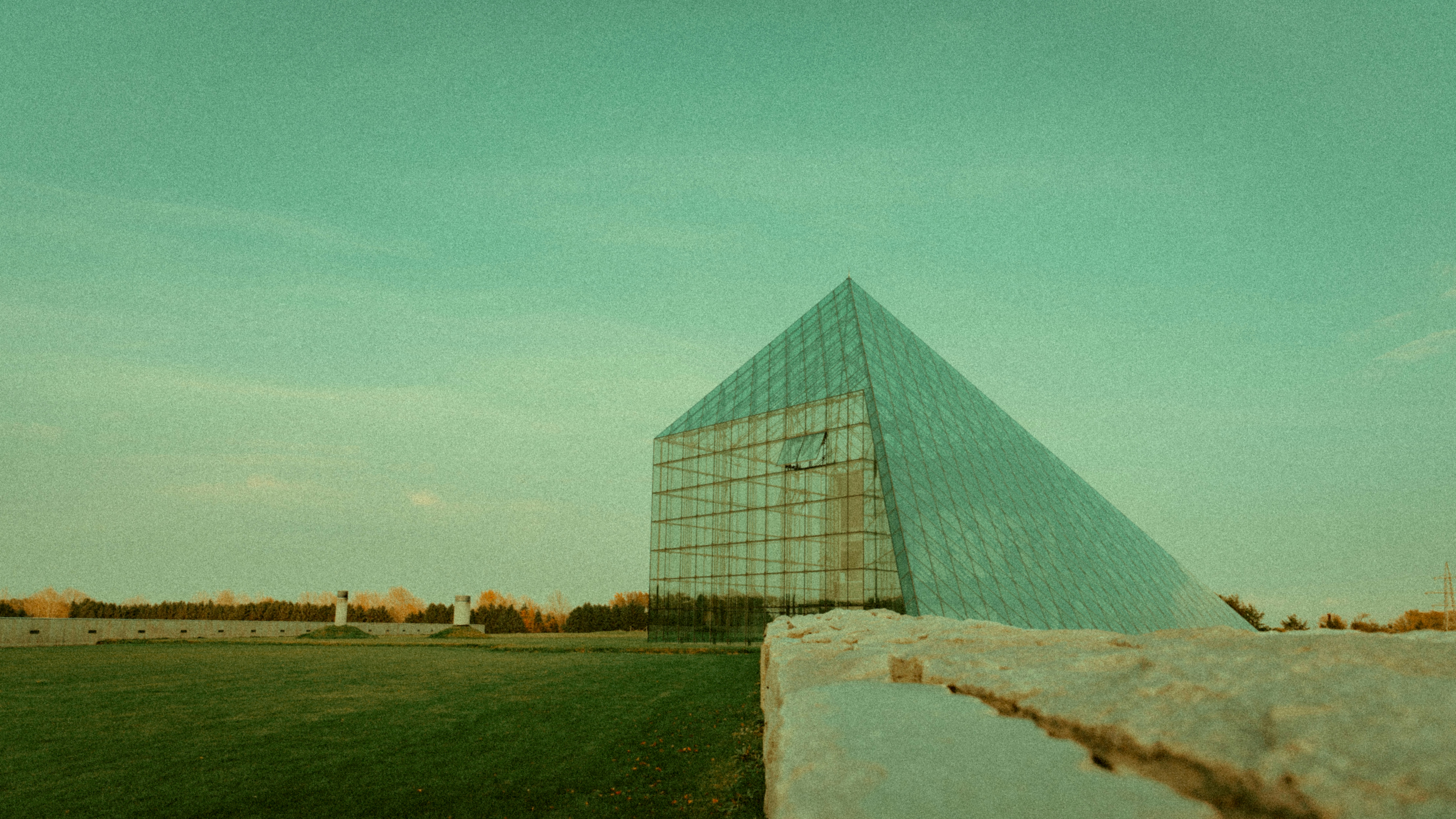 a very tall glass building sitting in the middle of a field