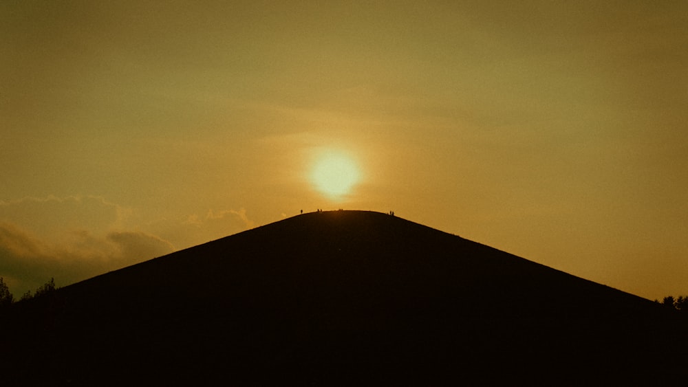 the sun is setting over the top of a hill