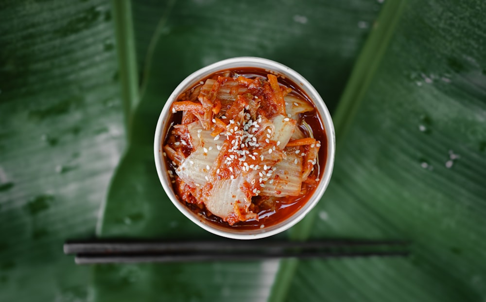 a bowl of food with chopsticks on a table