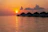 A couple enjoying a romantic sunset from their overwater villa in the Maldives.
