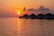 Smiling traveler enjoying a sunset over a Maldives beach bungalow.
