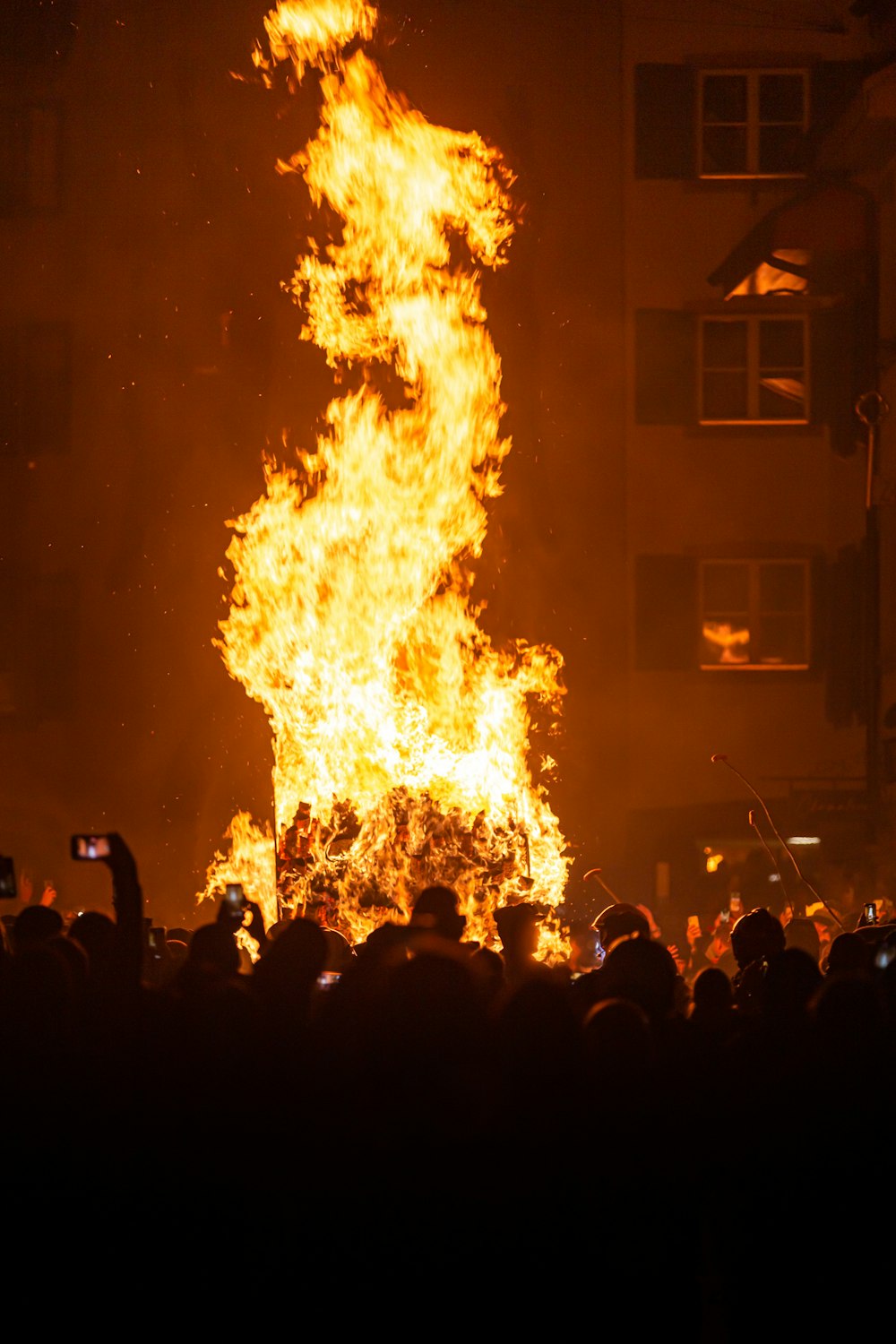 um grande grupo de pessoas em pé ao redor de um incêndio