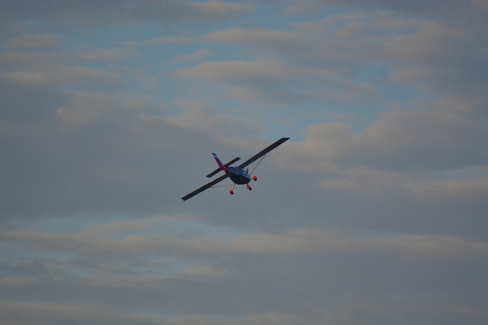 un petit avion volant dans un ciel nuageux