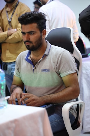 A business leader seated on an ergonomic chair, interacting with a digital interface surrounded by blue and white light.