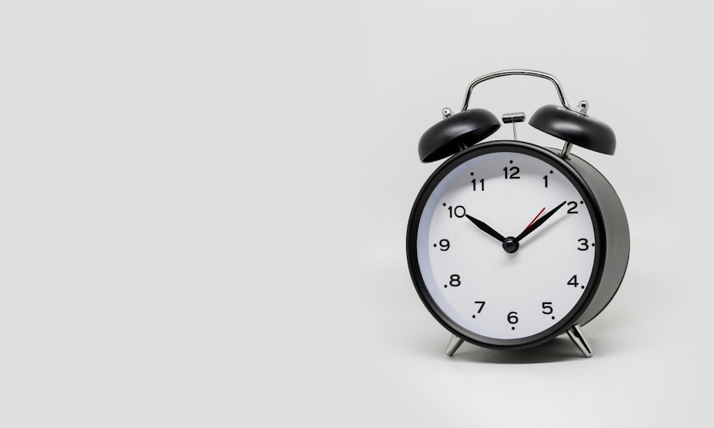 a black and white alarm clock on a white background