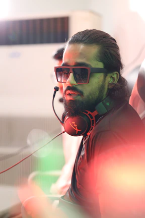 Close-up of an Indian male voice process specialist wearing a headset in a vibrant BPO environment.