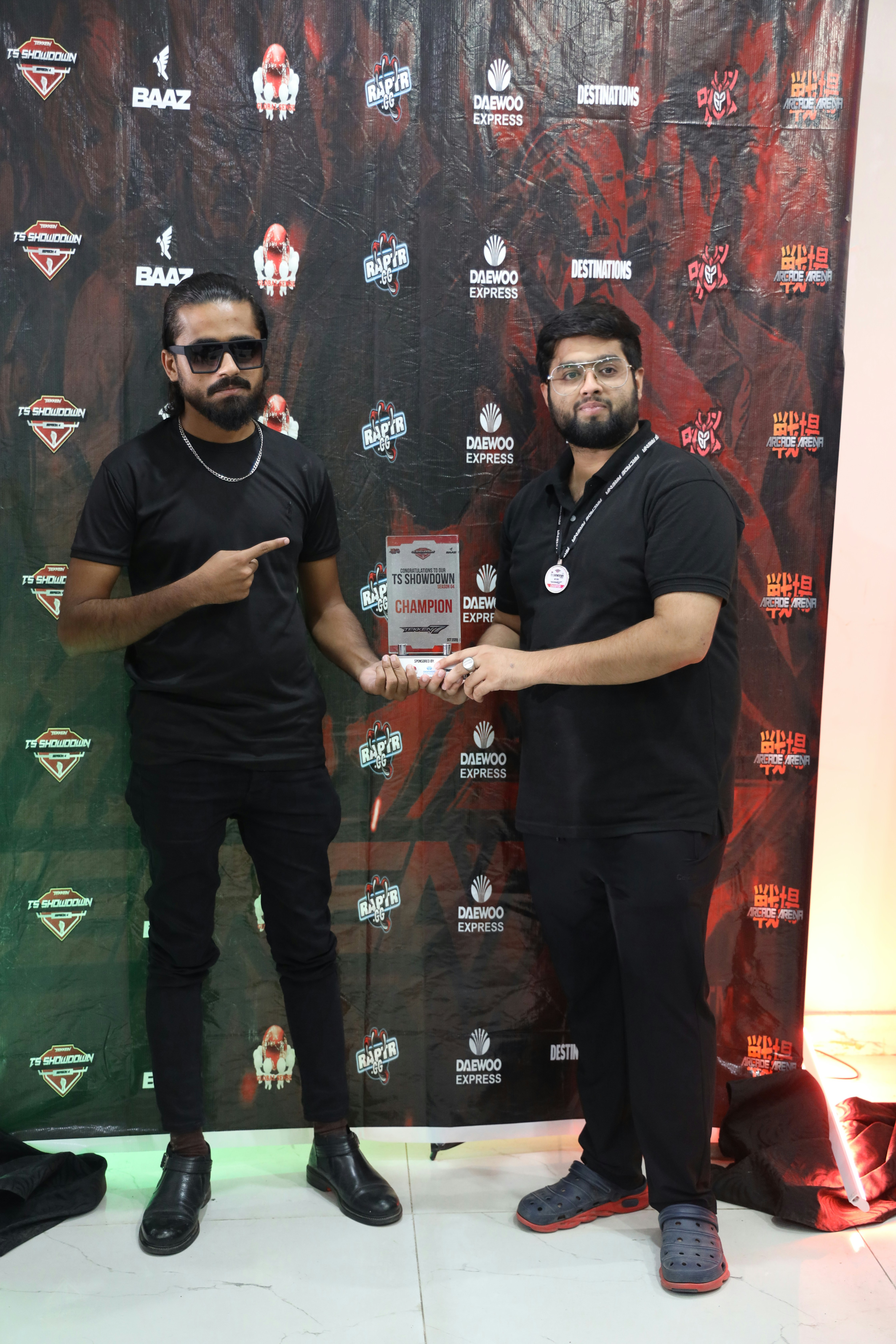 two men standing next to each other in front of a wall