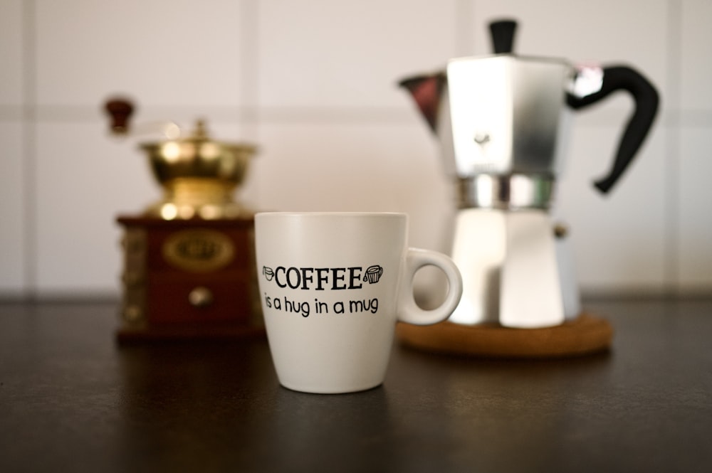 a coffee cup sitting on a table next to a coffee maker