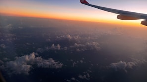 Aerial shot of a sleek jet soaring above the clouds at sunset.