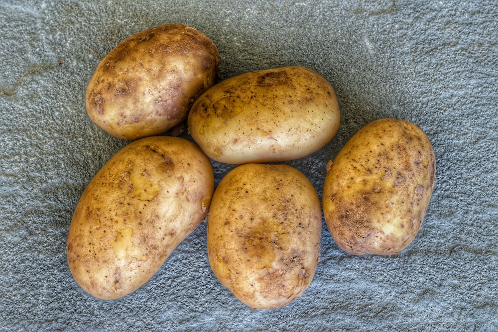 four potatoes sitting on a towel on the ground