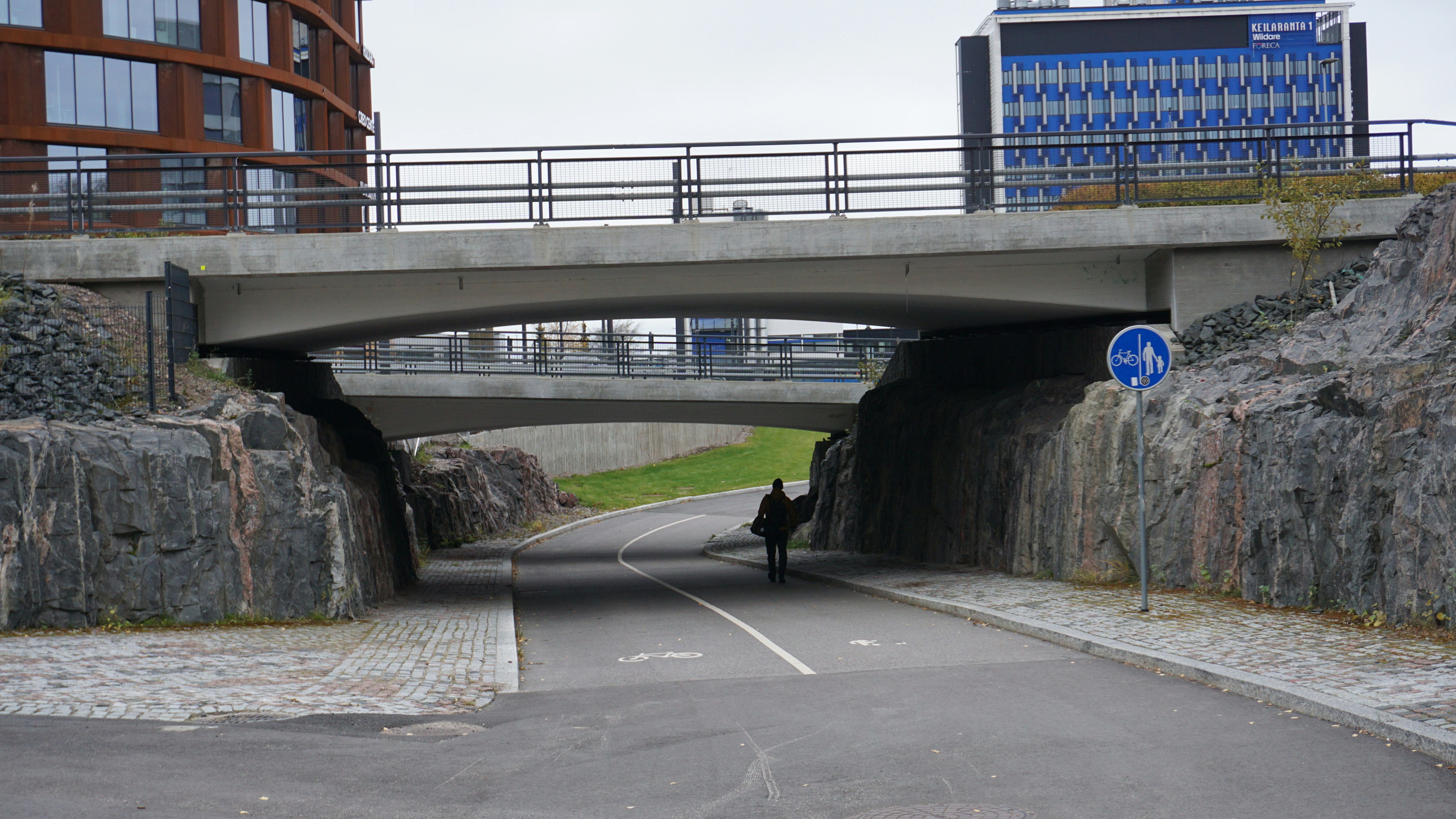 eine Person, die mit einem Fahrrad eine Straße unter einer Brücke hinunterfährt