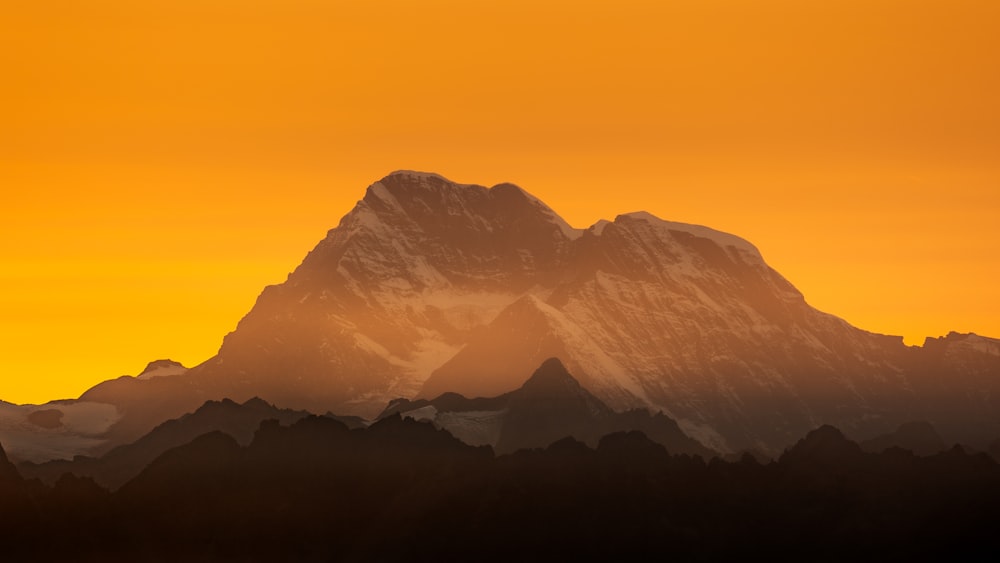 a snow covered mountain with a yellow sky in the background