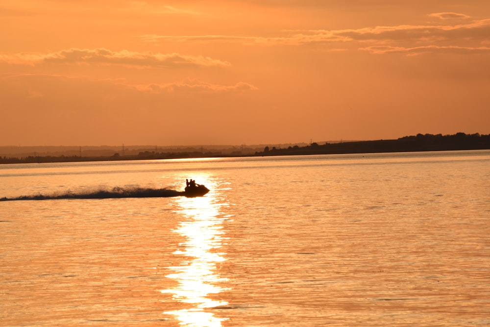 a person on a boat in the water at sunset