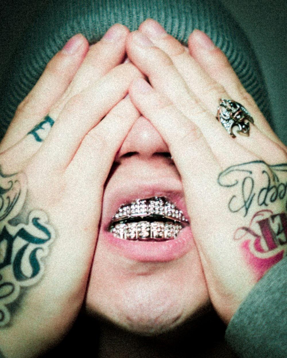 a man with tattoos covering his eyes with his hands