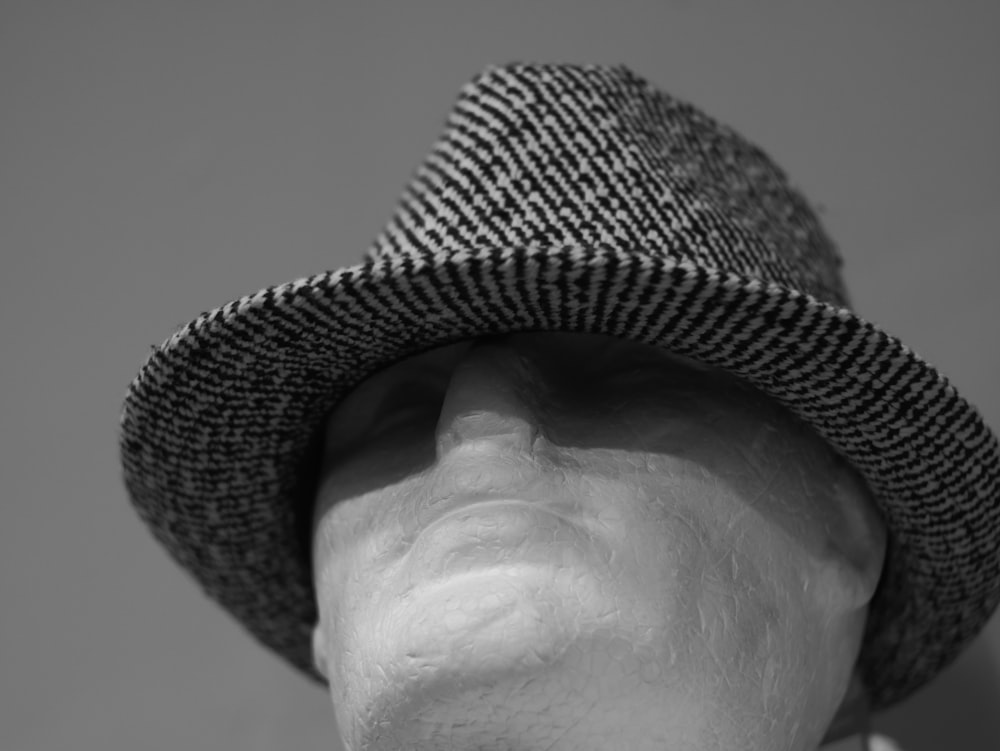 a white mannequin head wearing a black and white hat