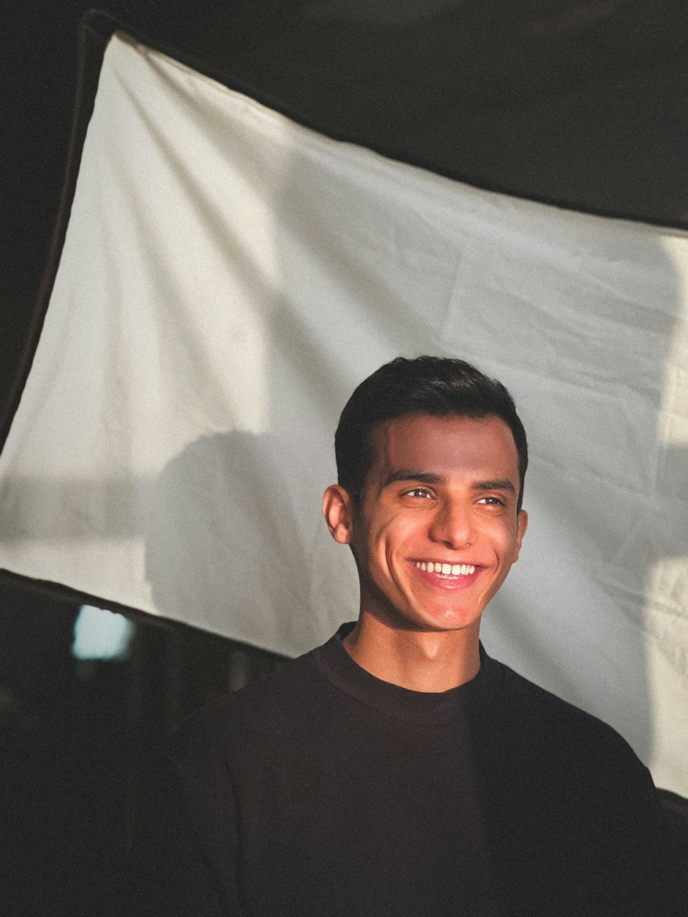 a young man smiles in front of a white backdrop
