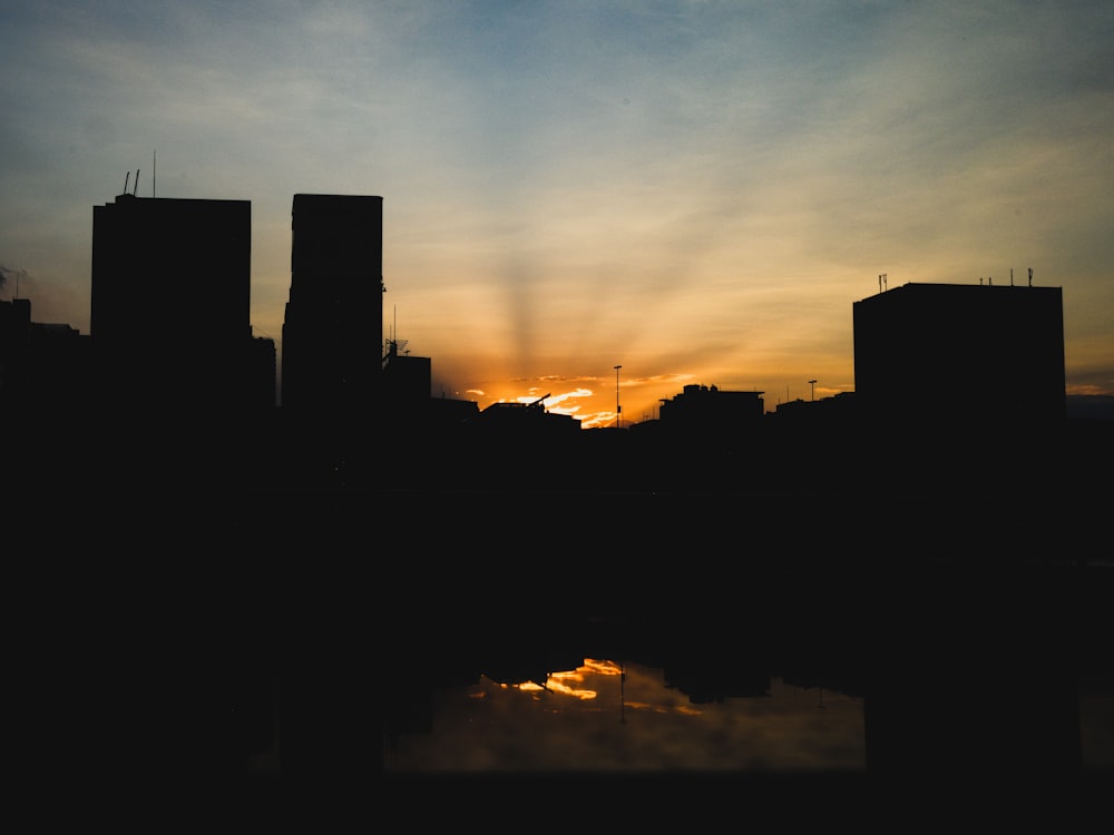 the sun is setting over a city with tall buildings