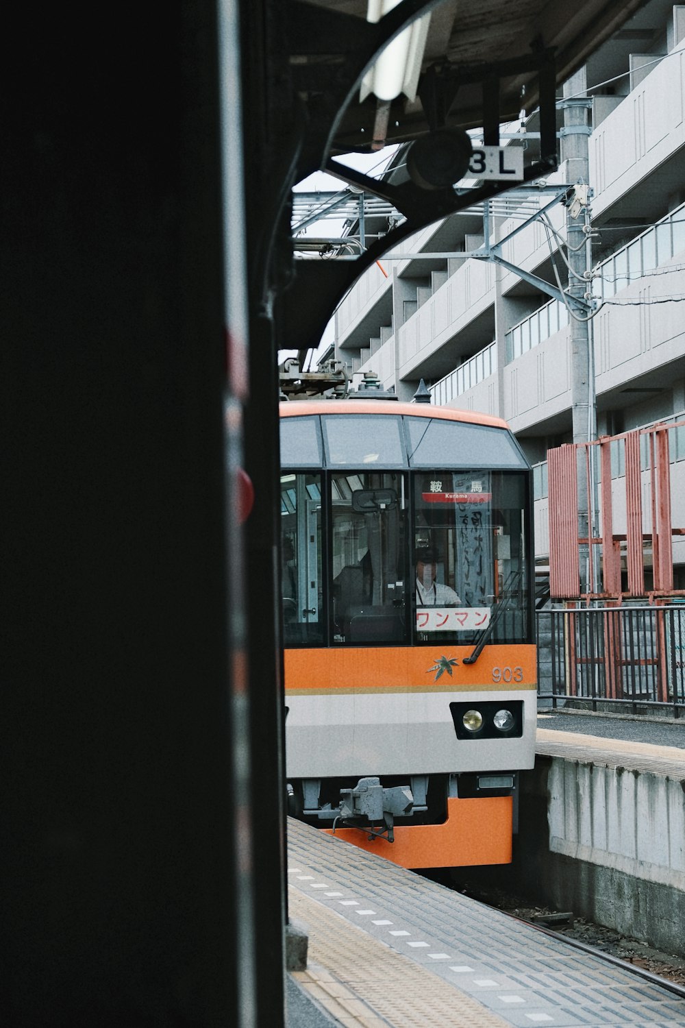 an orange and white train pulling into a train station