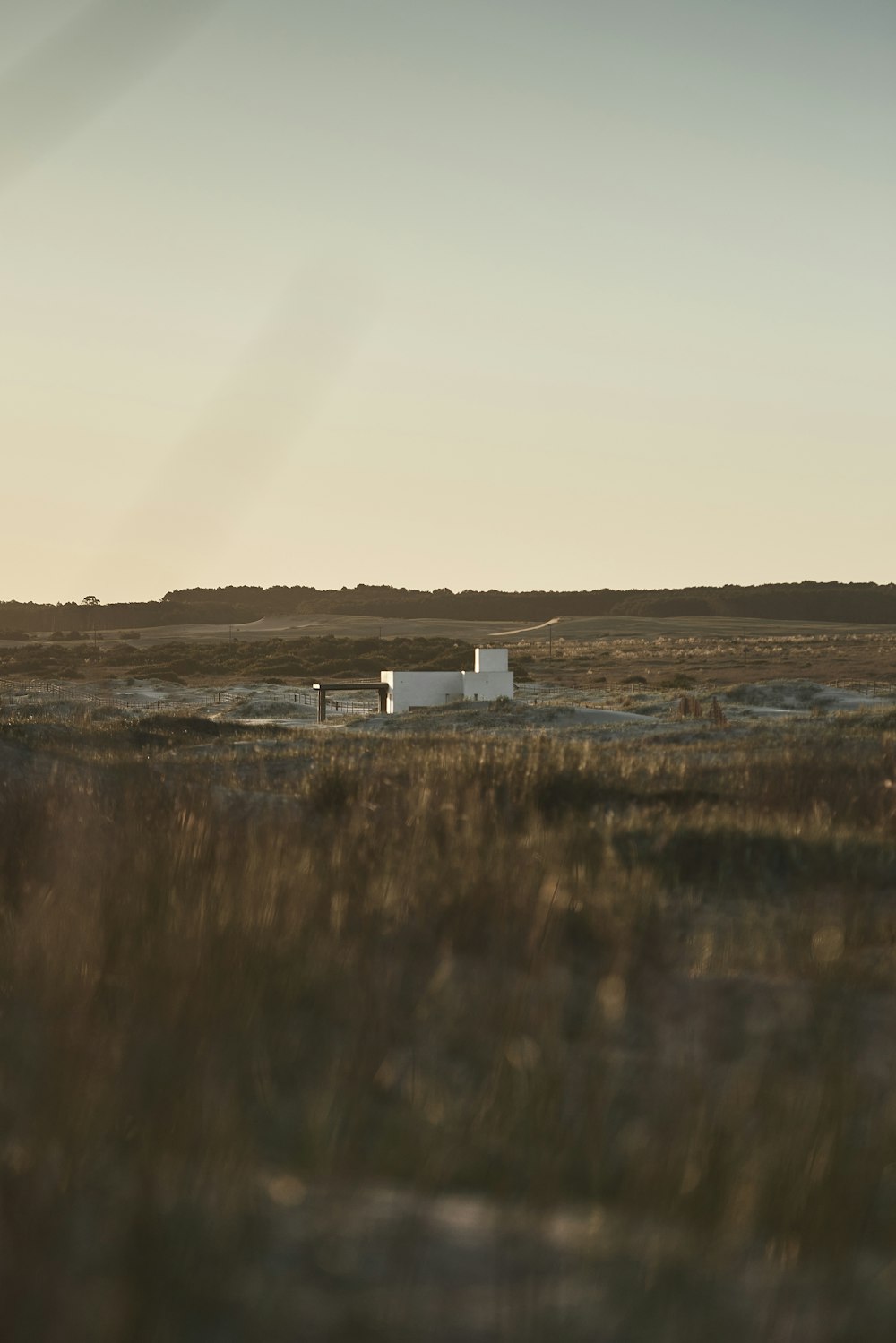 a small white building sitting in the middle of a field