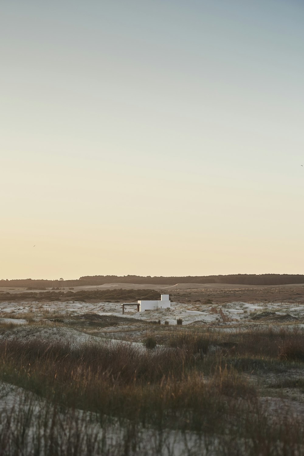 a small white building sitting in the middle of a field