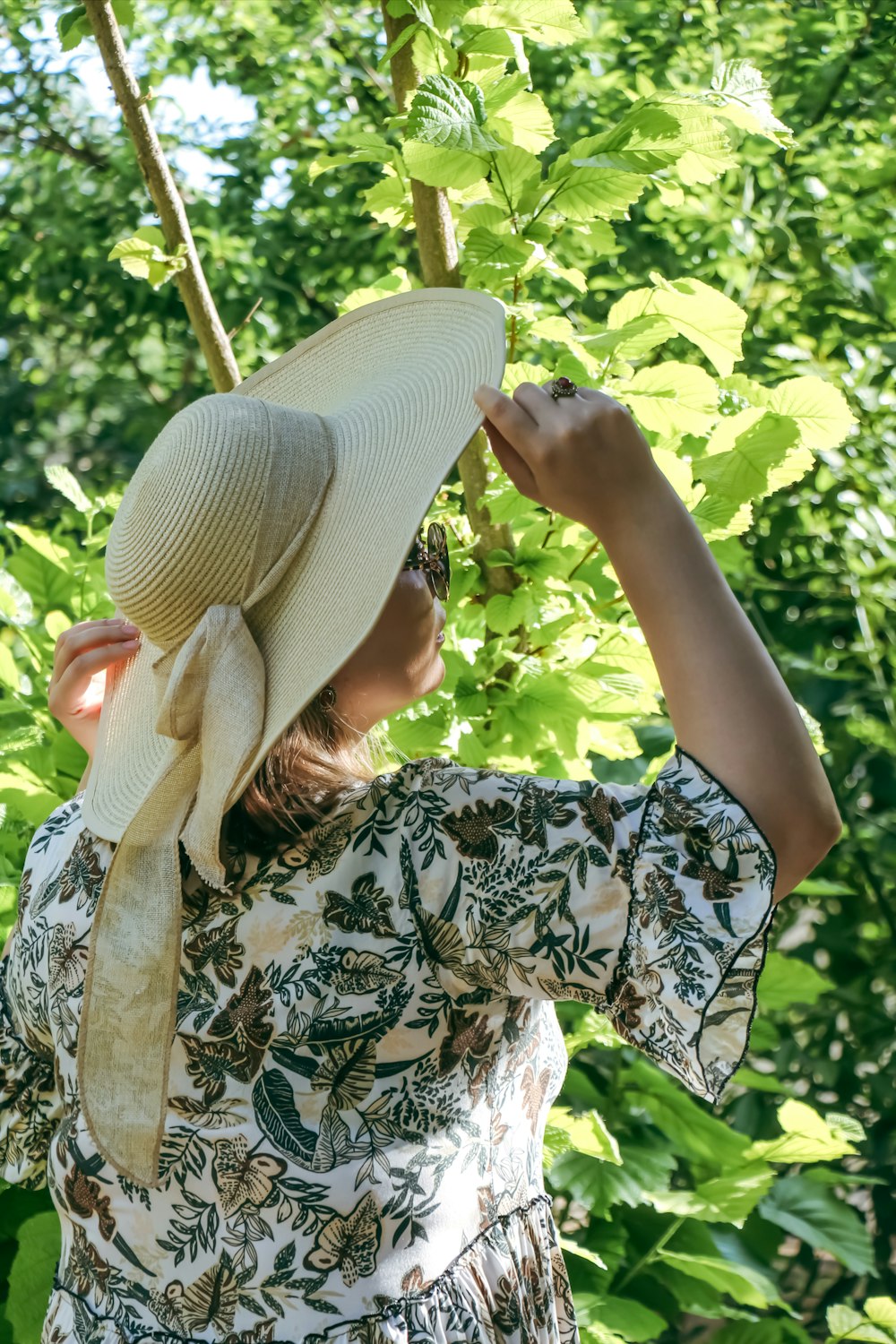 una donna in un vestito e un cappello in piedi davanti a un albero