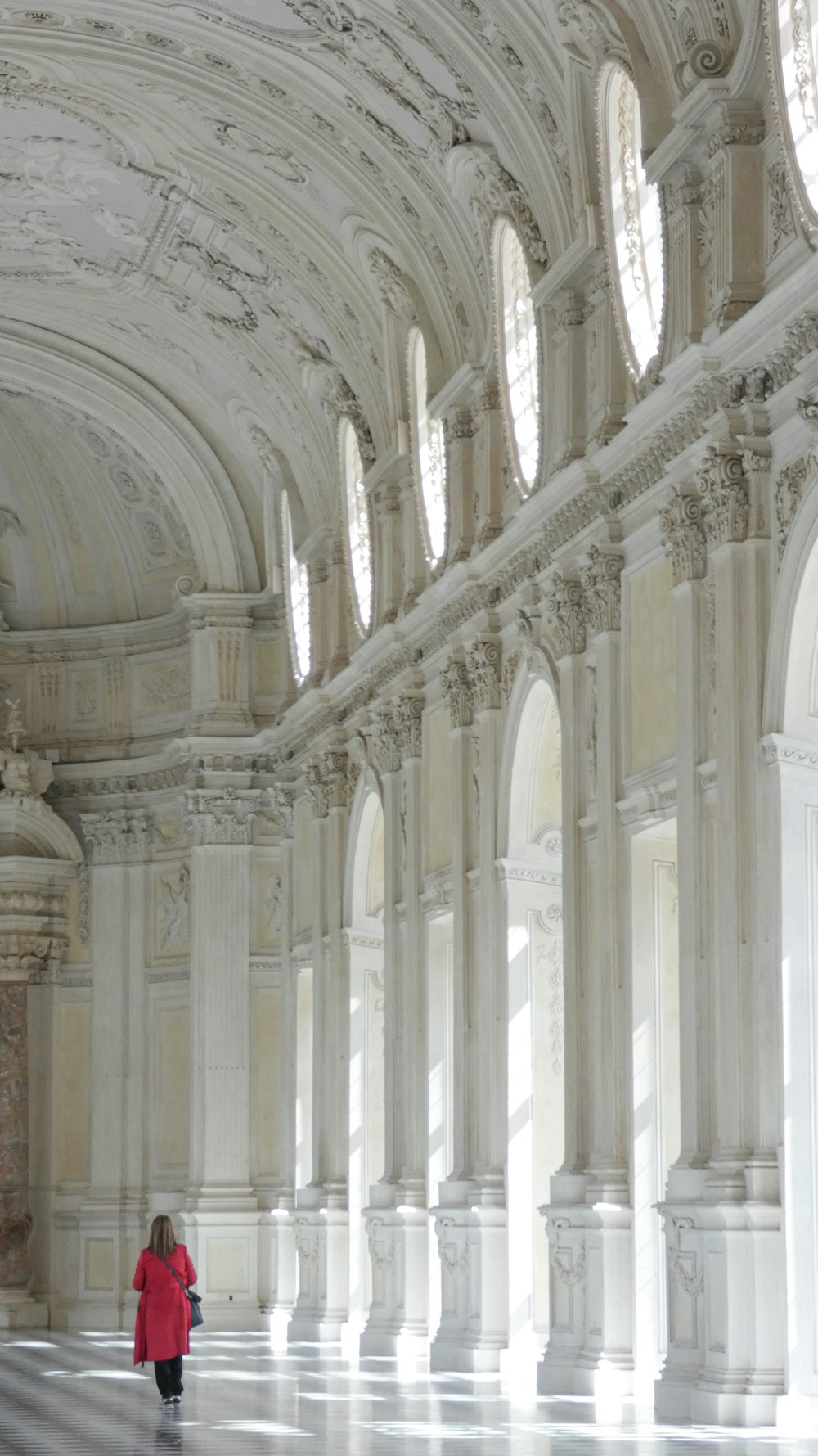 a woman in a red coat is walking in a large building