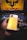 A person is holding a smartphone with a yellow back and a visible camera module. The phone features branding that reads 'realme' and 'DARE TO LEAP'. In the background, there is a laptop with a colorful backlit keyboard and a screen displaying a logo and the text 'TUF GAMING' in bold letters.