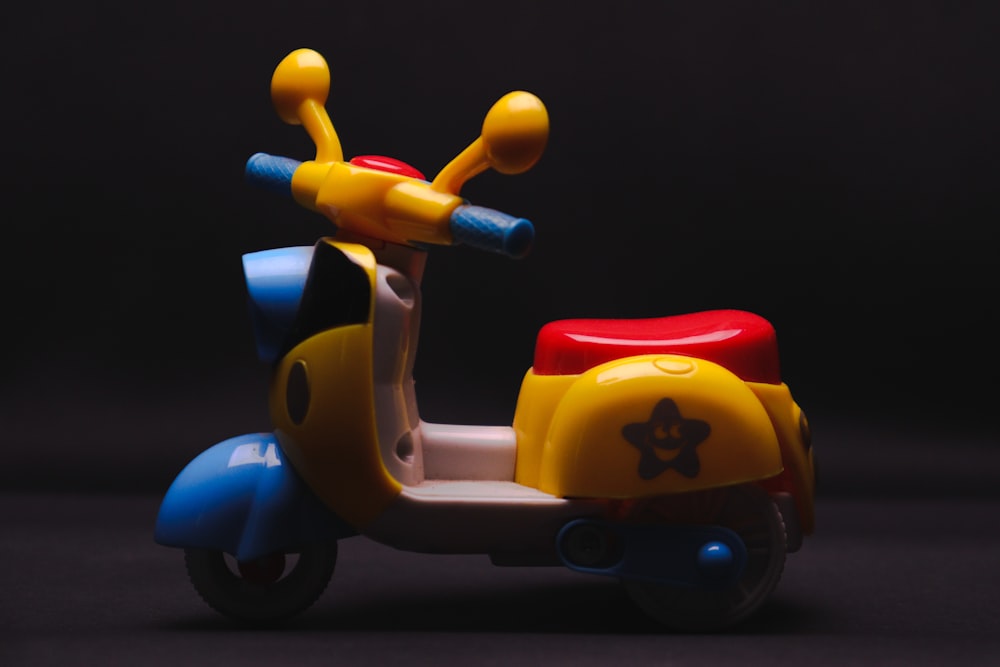 a toy scooter with a red, yellow, and blue seat