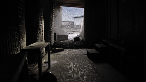 A tense moment inside a dimly lit bunker filled with supplies and lurking dangers.