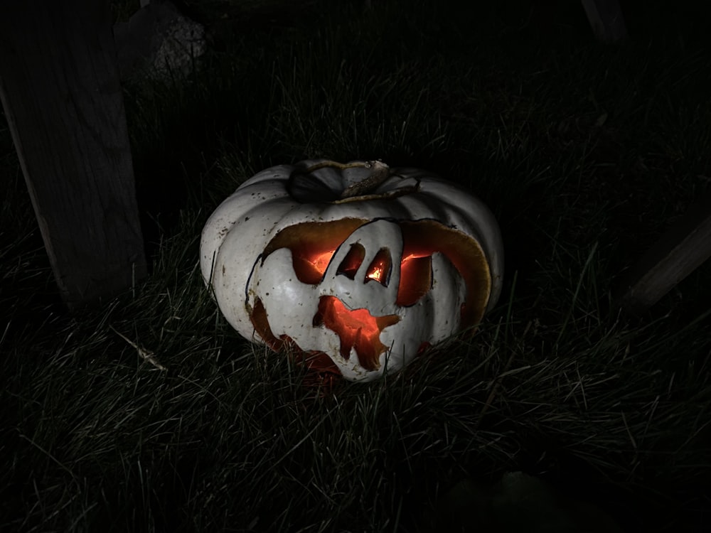 a lit up pumpkin sitting in the grass