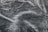 A close-up texture of dark fabric with visible water droplets creating a pattern across the surface. The material appears to be slightly wrinkled, adding depth and interest to the image.