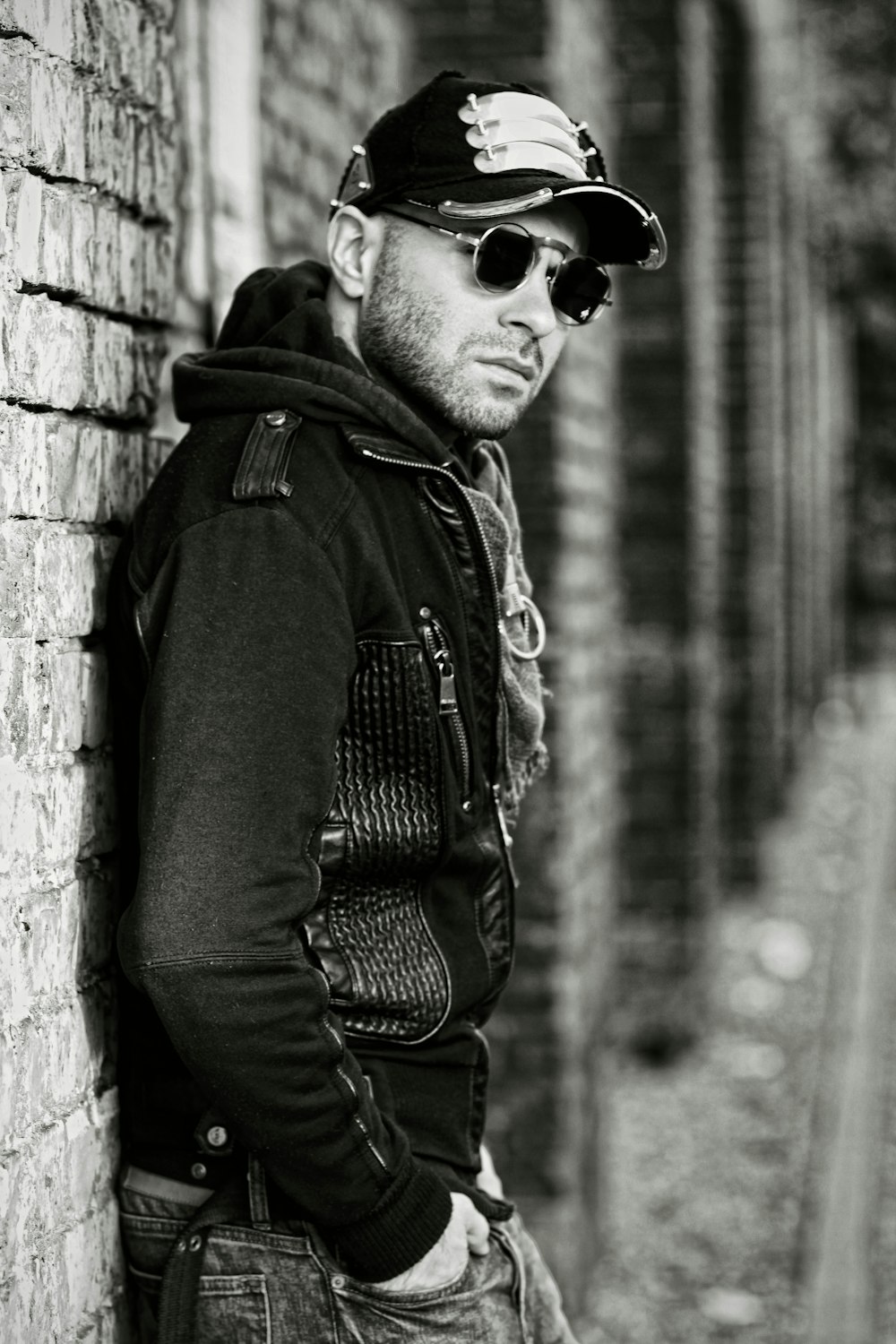 a man leaning against a brick wall wearing sunglasses