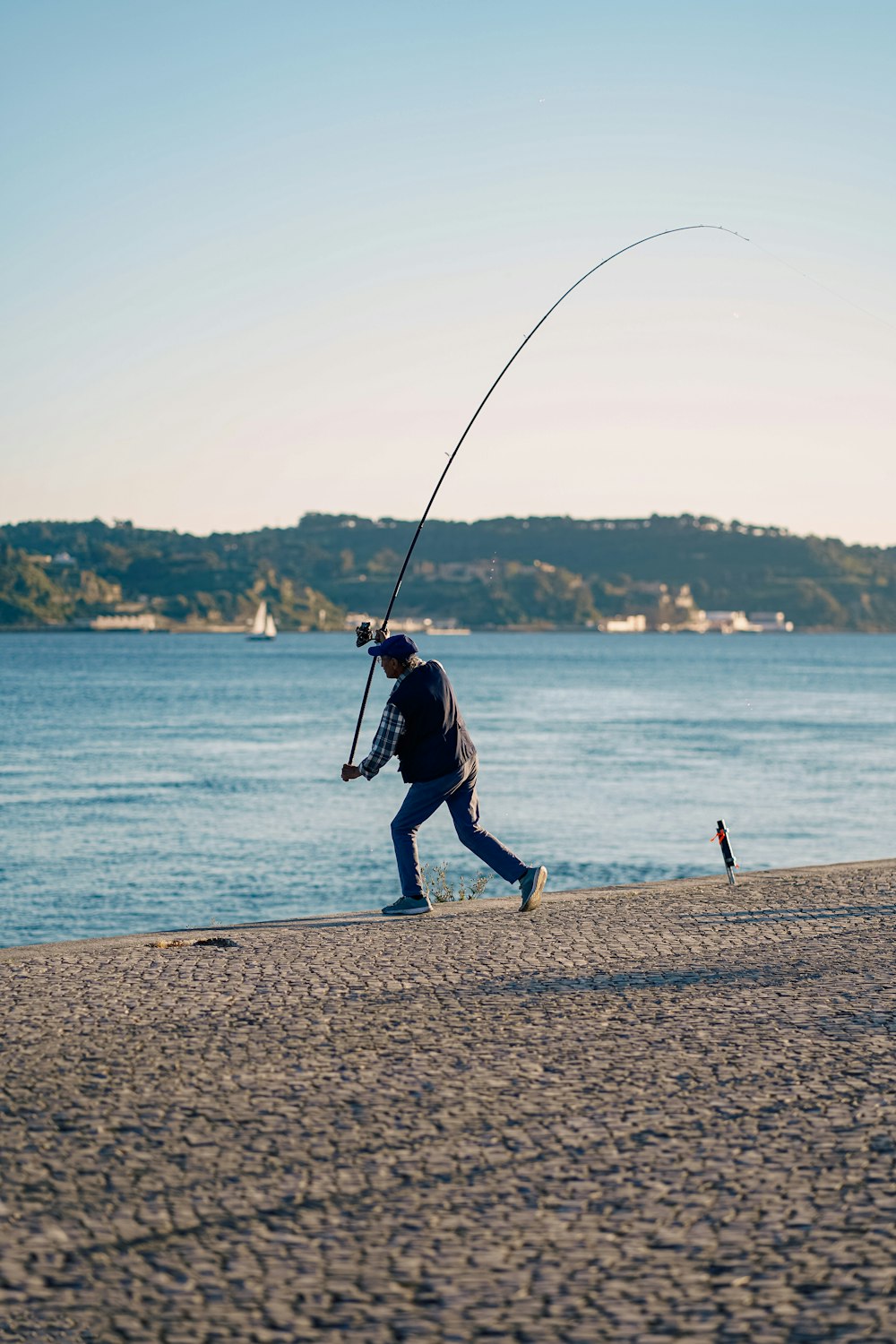 a man walking on a beach while holding a fishing pole