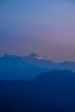 A serene mountain range bathed in the cool tones of early evening.