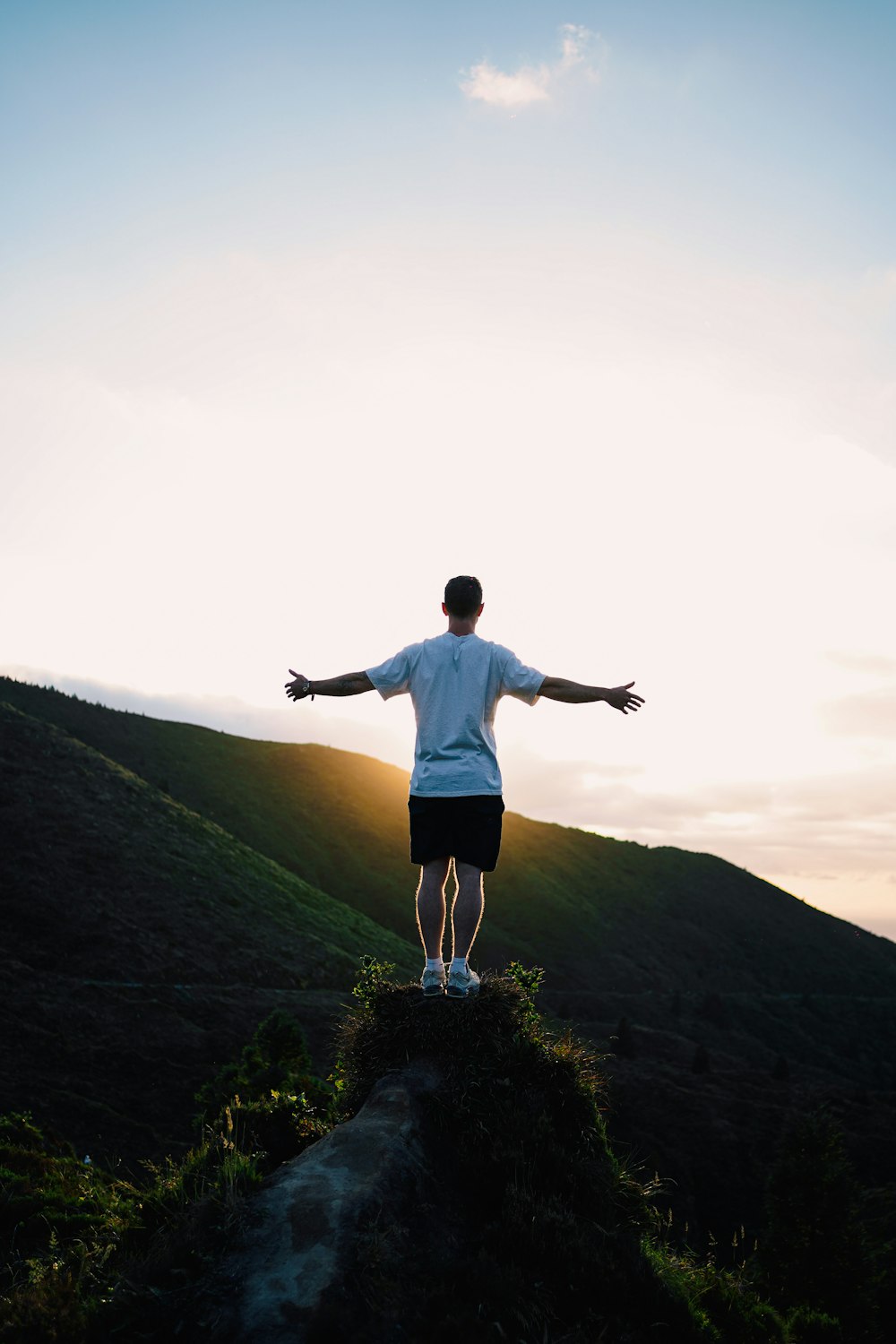 a man standing on top of a lush green hillside