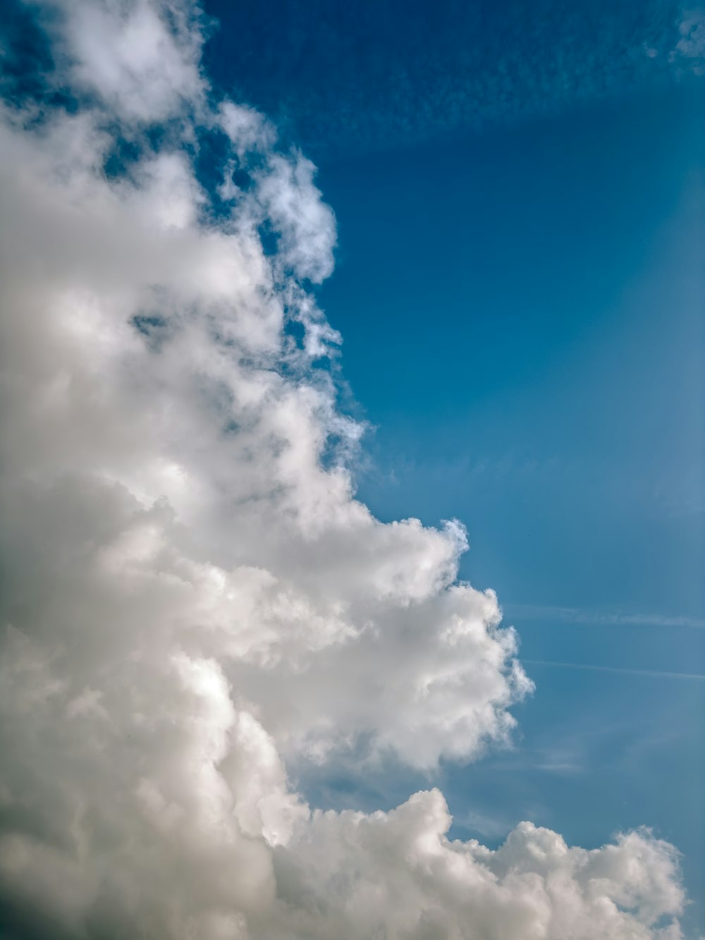 a plane flying through a cloudy blue sky