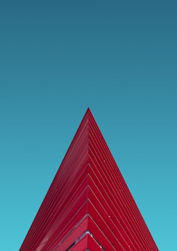 a red triangular shaped building against a blue sky