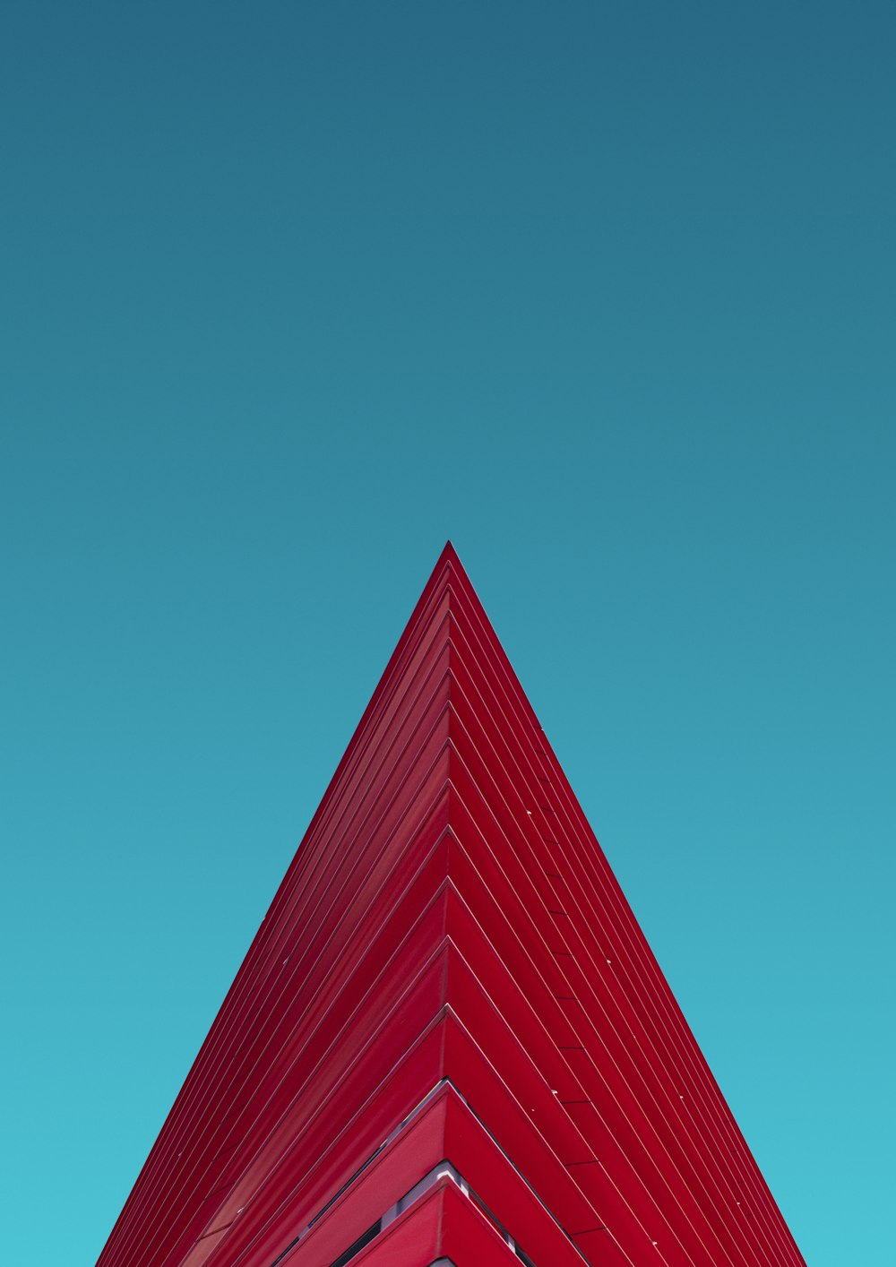 a red triangular shaped building against a blue sky