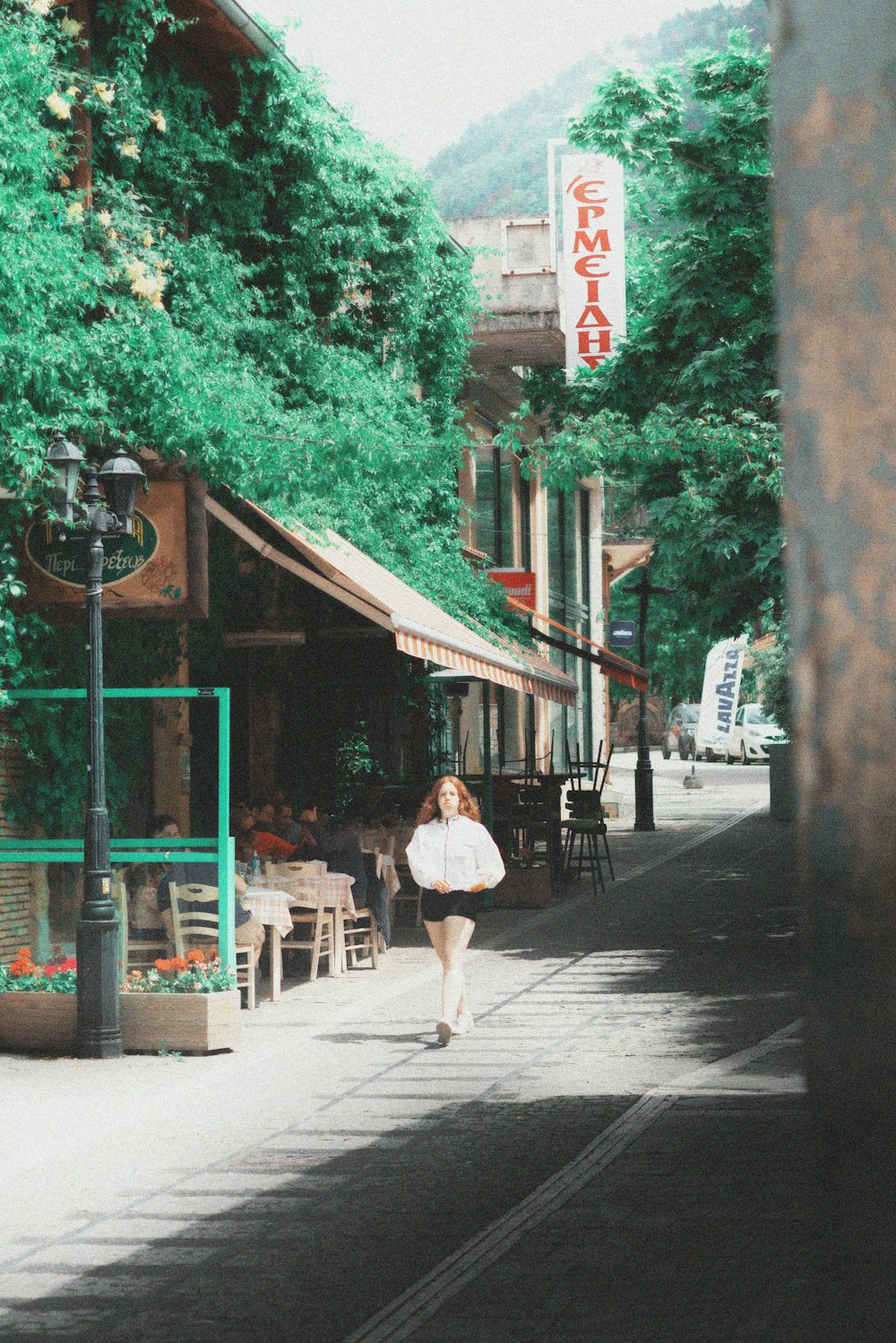 a woman walking down a street past a restaurant