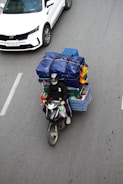 a person riding a motorcycle with a cart of items on the back of it