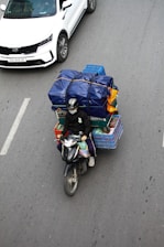 a person riding a motorcycle with a cart of items on the back of it