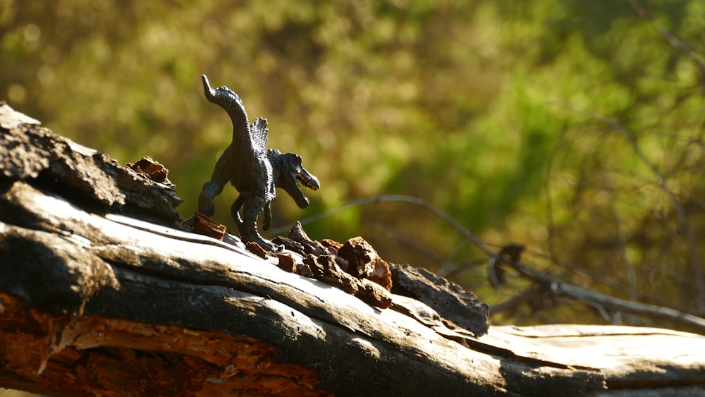 a small toy dinosaur standing on top of a log