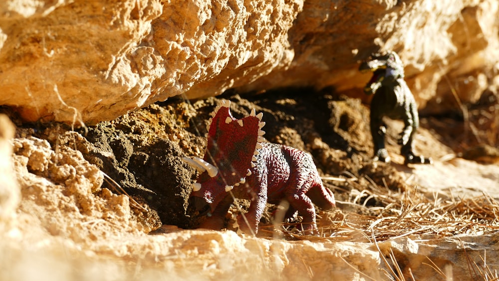a toy dinosaur in front of a rock formation