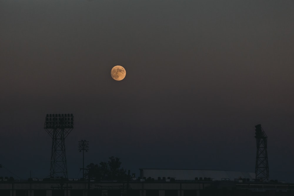 uma lua cheia nascendo sobre um campo de beisebol