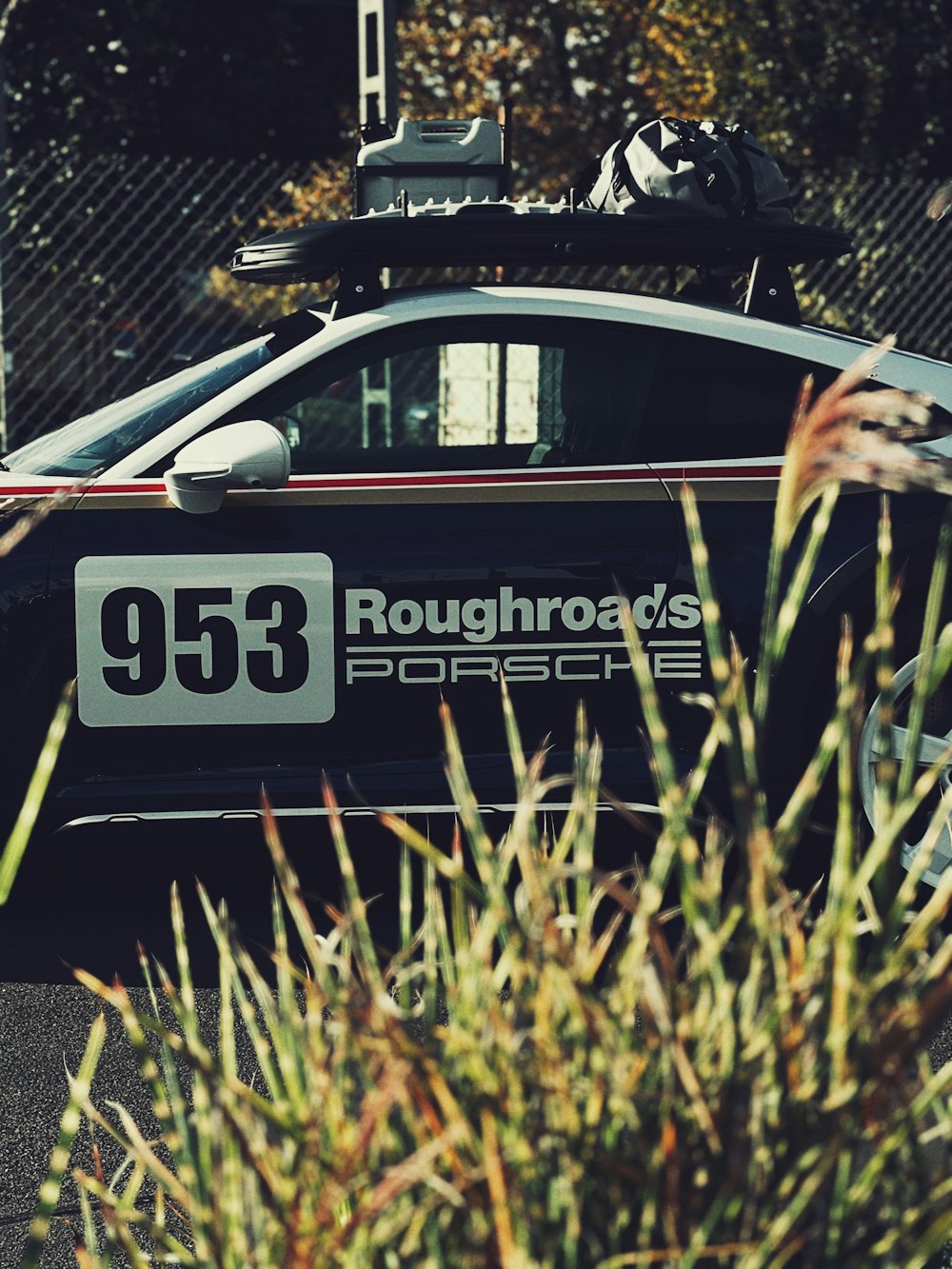 a car parked in front of a fence with a sign on it