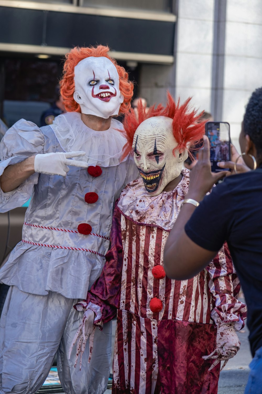 a man taking a picture of a clown with a cell phone